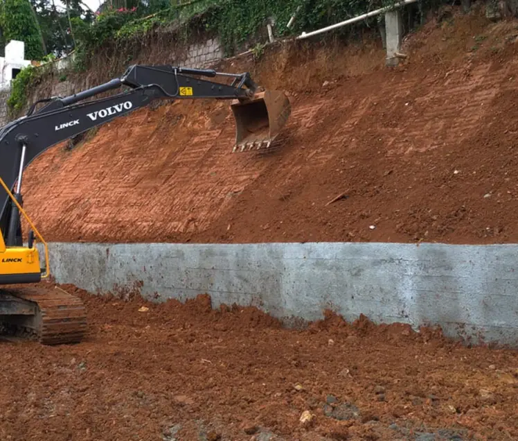 Muro de arrimo em concreto armado ao pé de um barranco cortado, com escavadeira, em Joinville (SC)