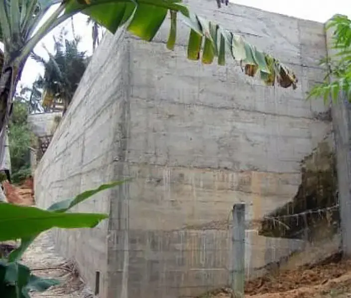 Muro de contenção alto em concreto armado, com as marcas das tábuas da fôrma